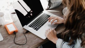 close up photography of woman sitting beside table while using macbook