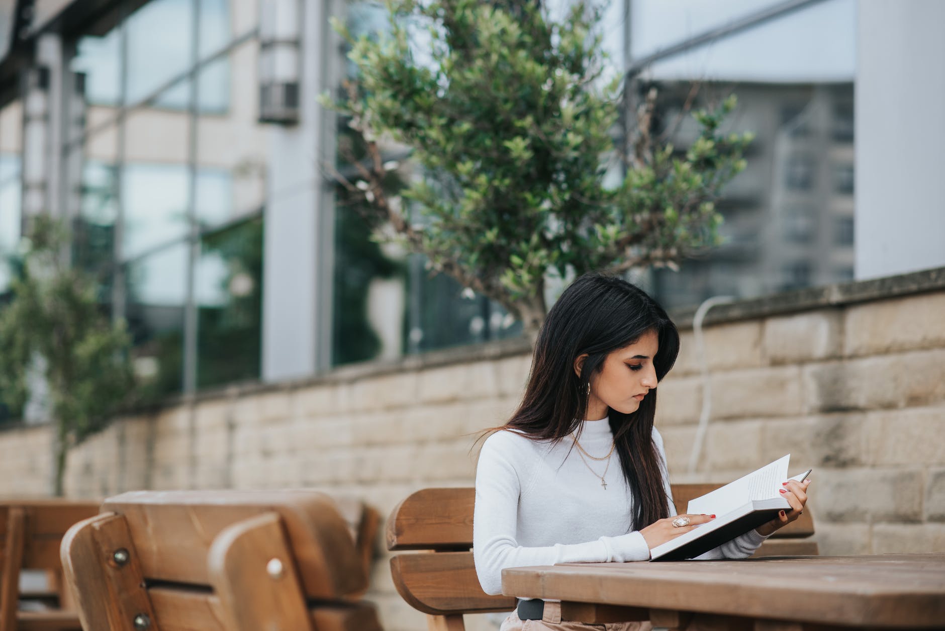 focused ethnic lady studying book in park